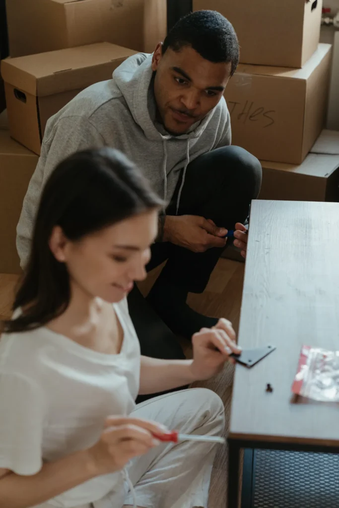Couple assembling a new table among moving boxes