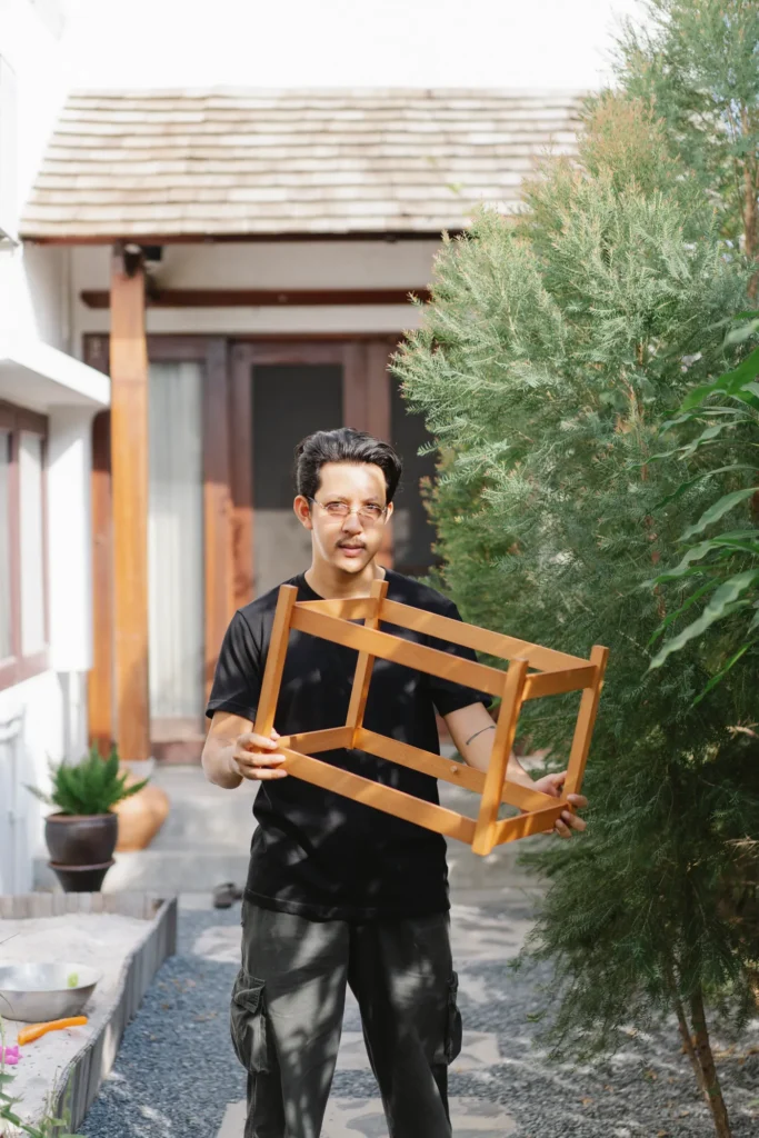 Man holding a wooden chair frame outdoors