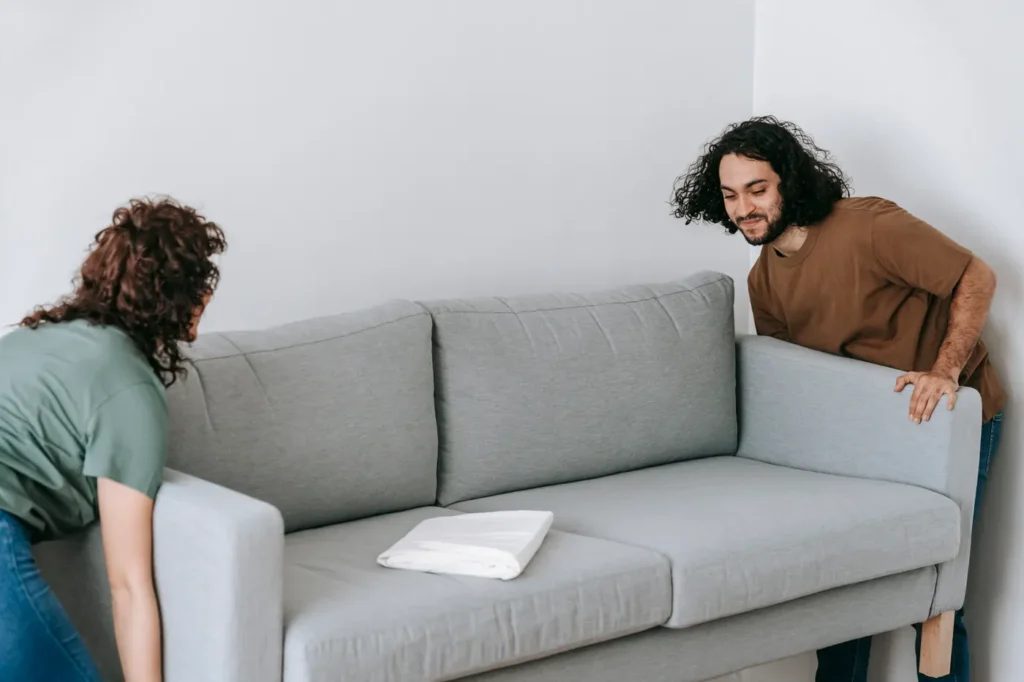 Couple setting up a new grey sofa