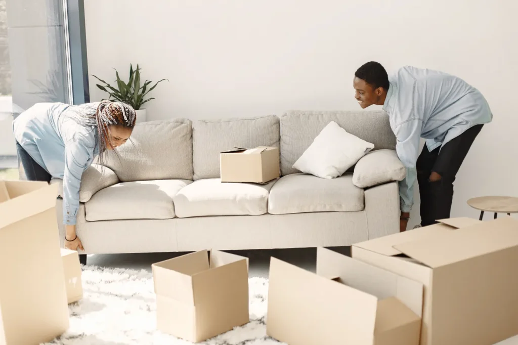 Couple unpacking a new sofa among boxes