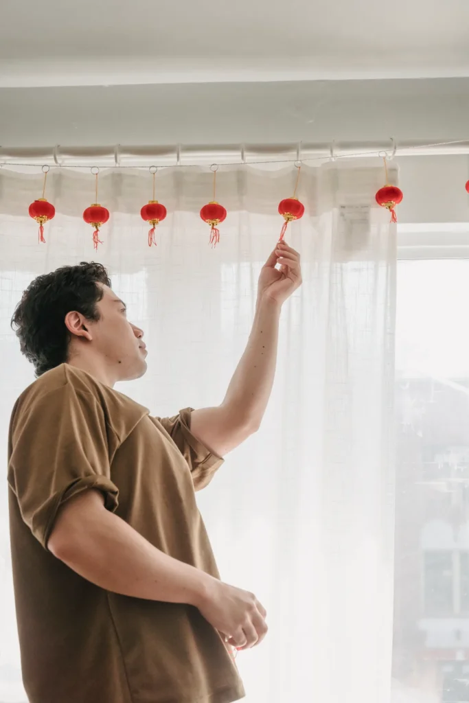 Man hanging sheer curtains on a rod