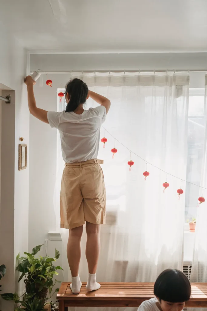 Woman hanging white curtains on a rod