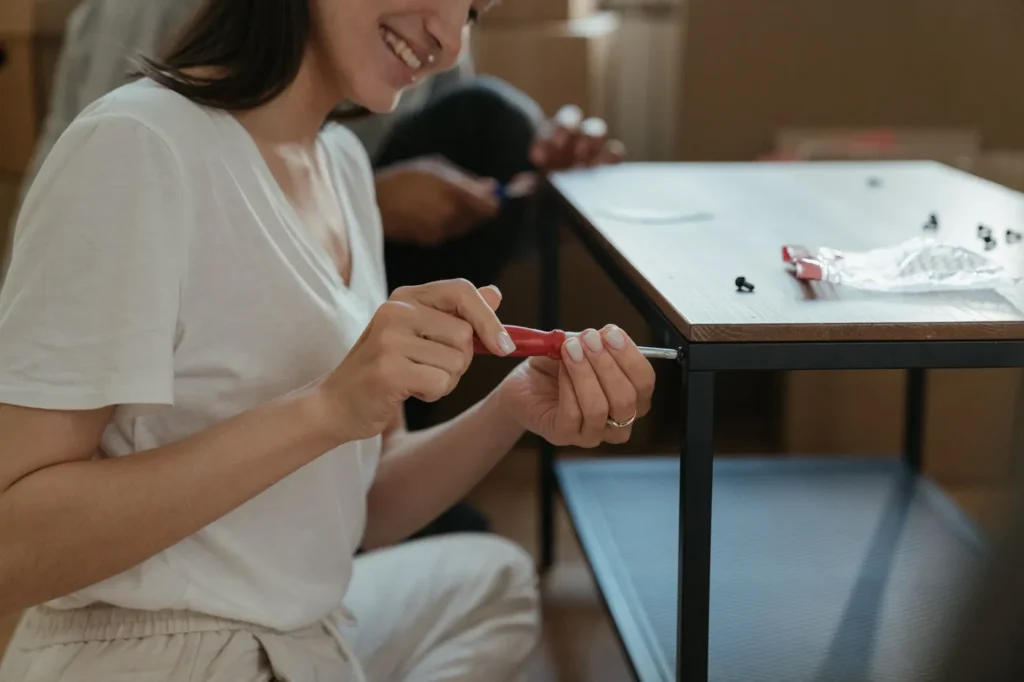Woman assembling a desk with a screwdriver