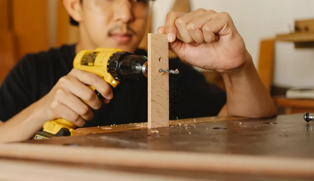 Man drilling a wooden furniture part