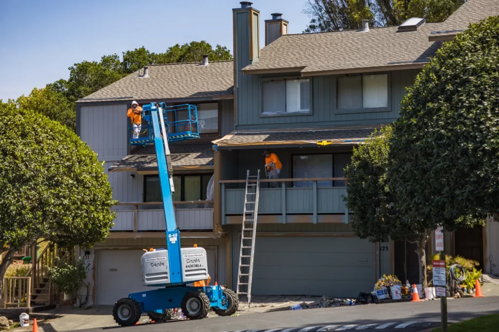 Painters on a lift painting a two-storey house