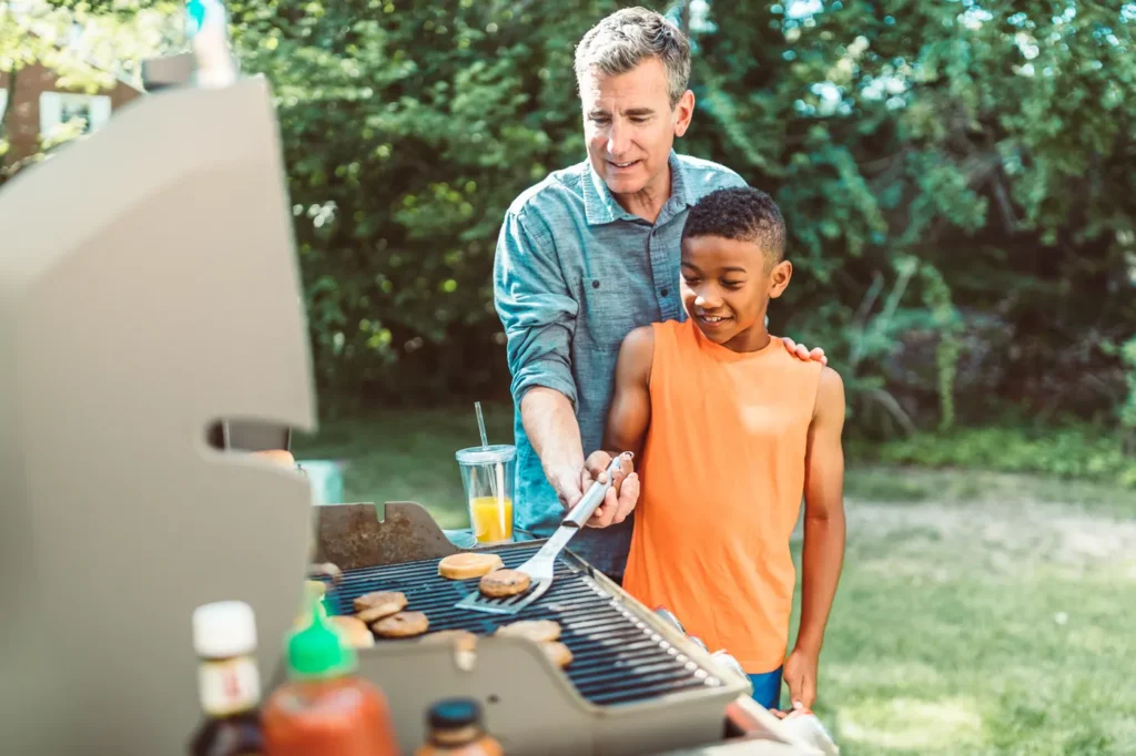 Father and son cooking together on a backyard grill