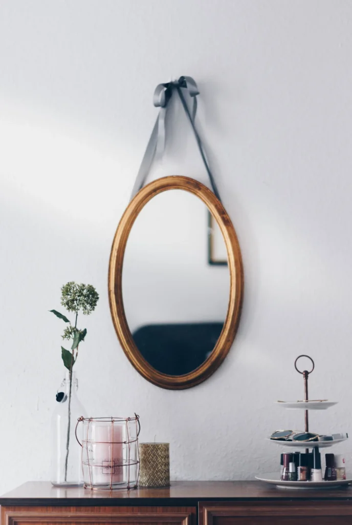 Round mirror on a leather strap on a white wall