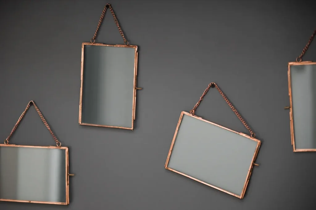 Three hanging mirrors on a grey wall