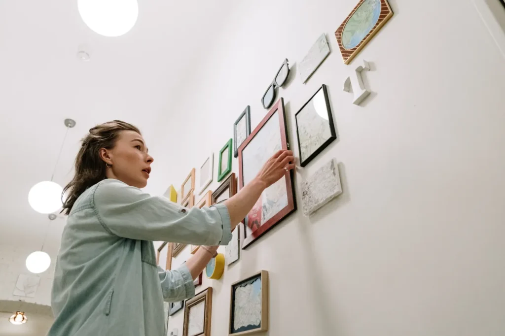 Woman hanging framed pictures on a living room wall