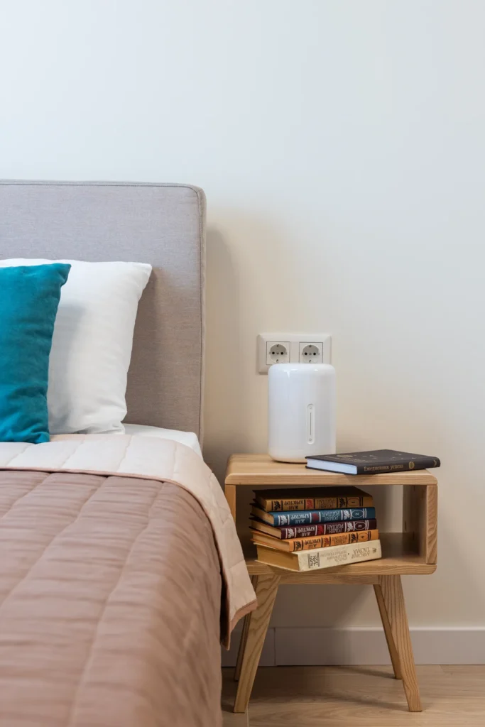 Wooden nightstand beside a made bed