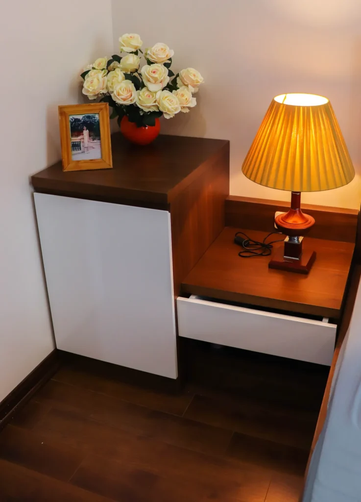 Nightstand with a lit lamp beside a bed