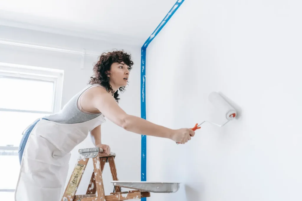 Woman painting a white wall with a roller