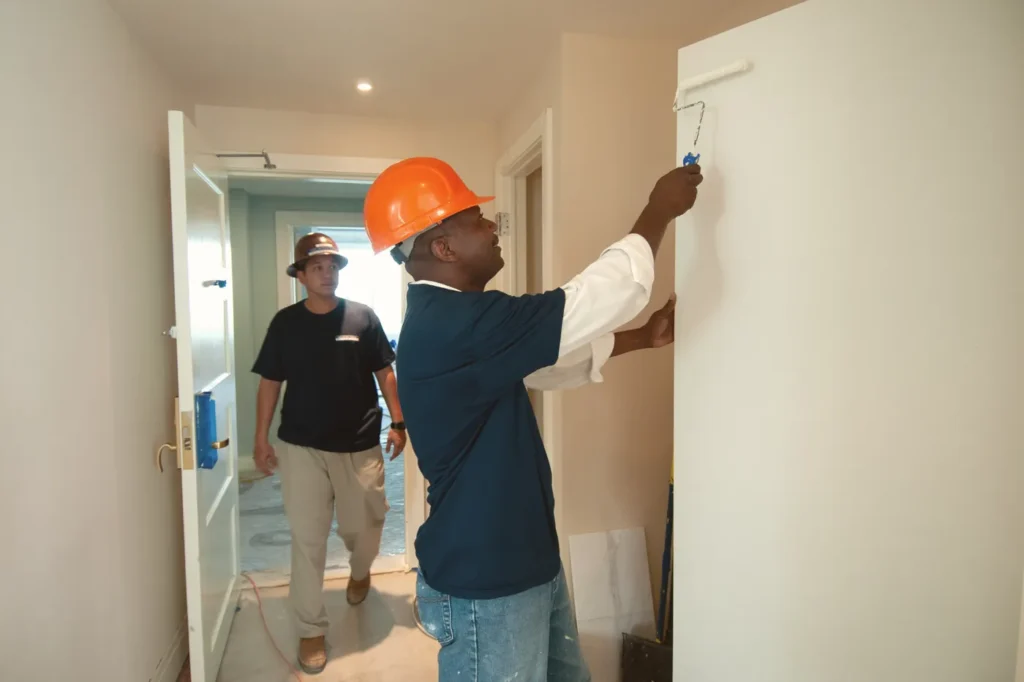 Painter rolling paint onto a hallway wall