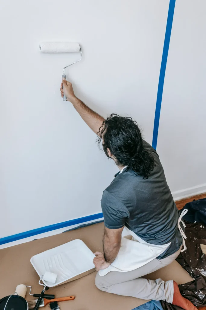 Person painting along taped edges near the floor