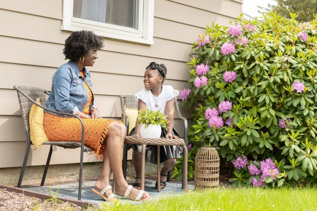 Mother and daughter relaxing in patio chairs outside their home
