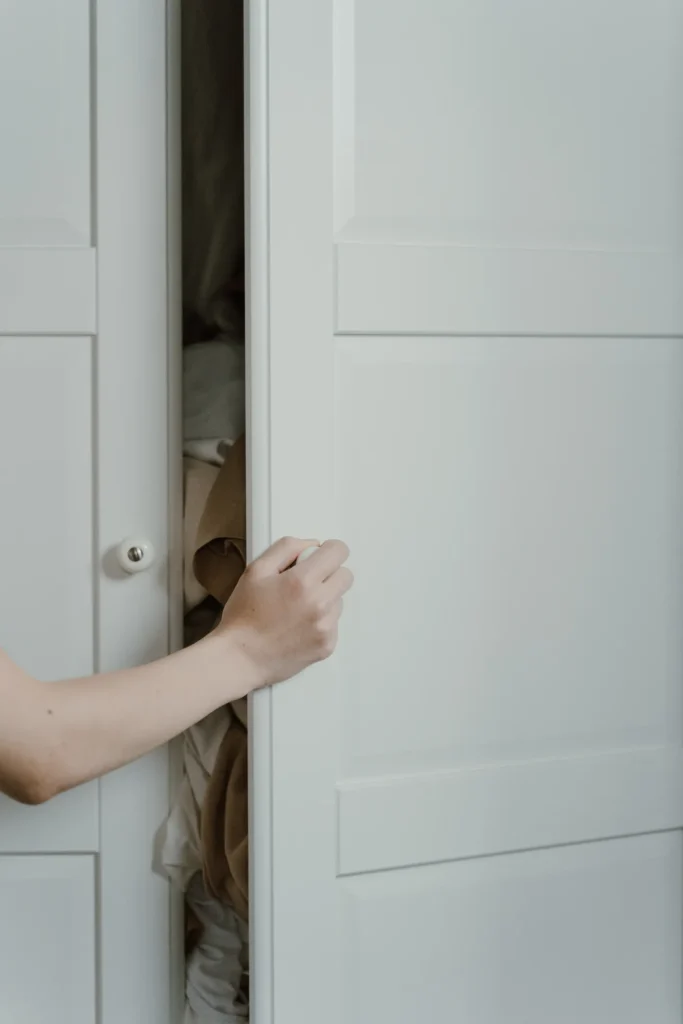 Hand opening a white wardrobe door