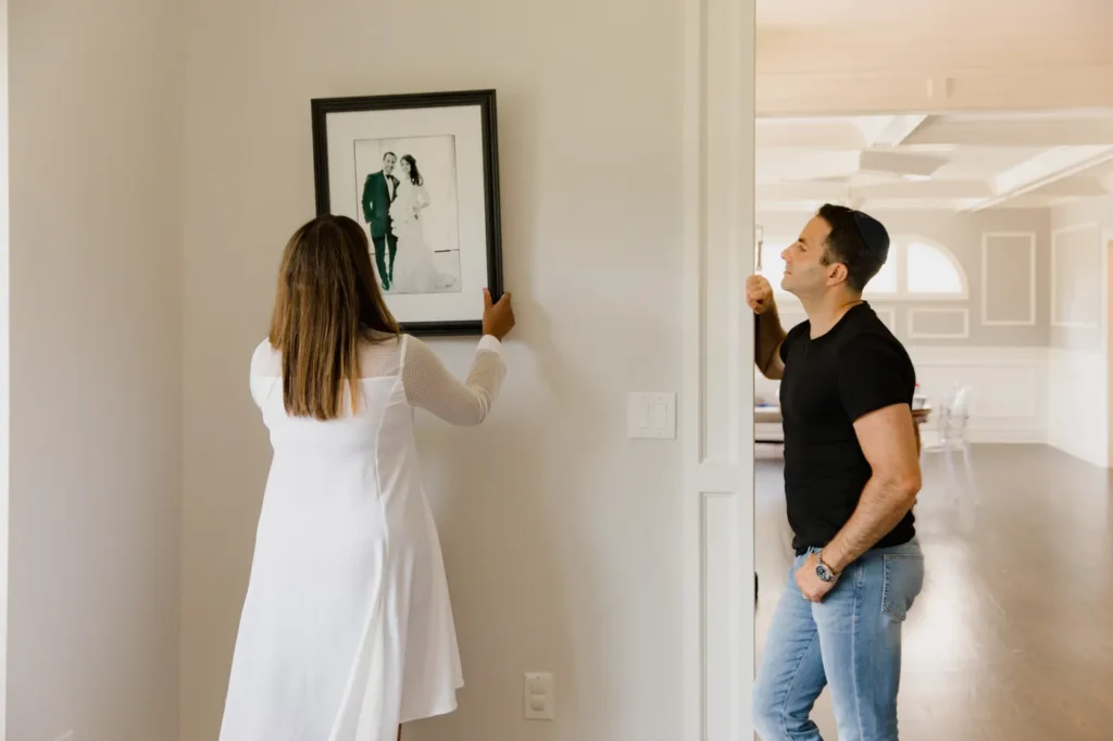 Couple hanging framed art in a hallway