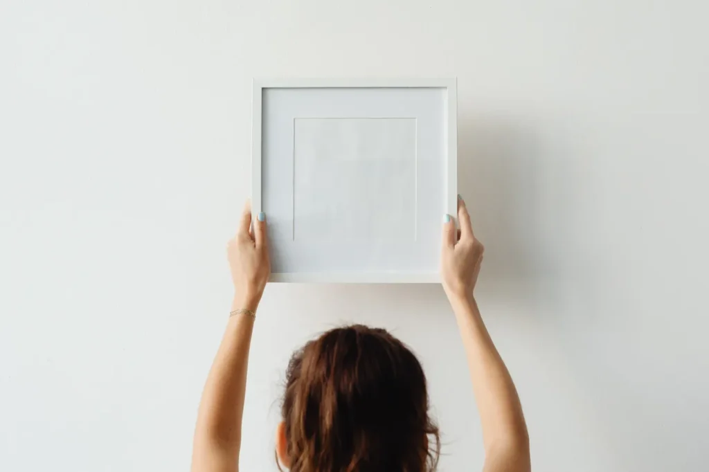 Woman lining up a white frame on a wall