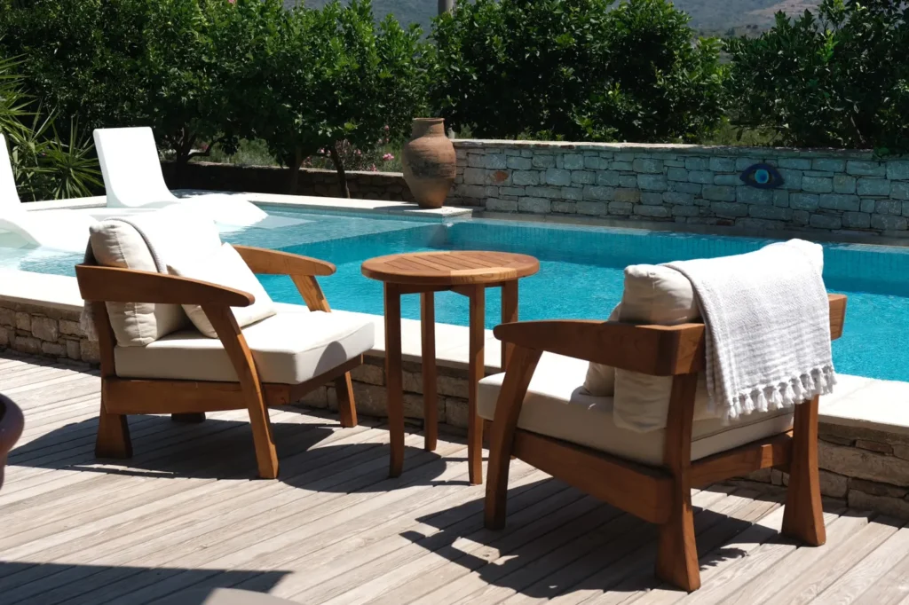Wooden lounge chairs and a side table beside a pool