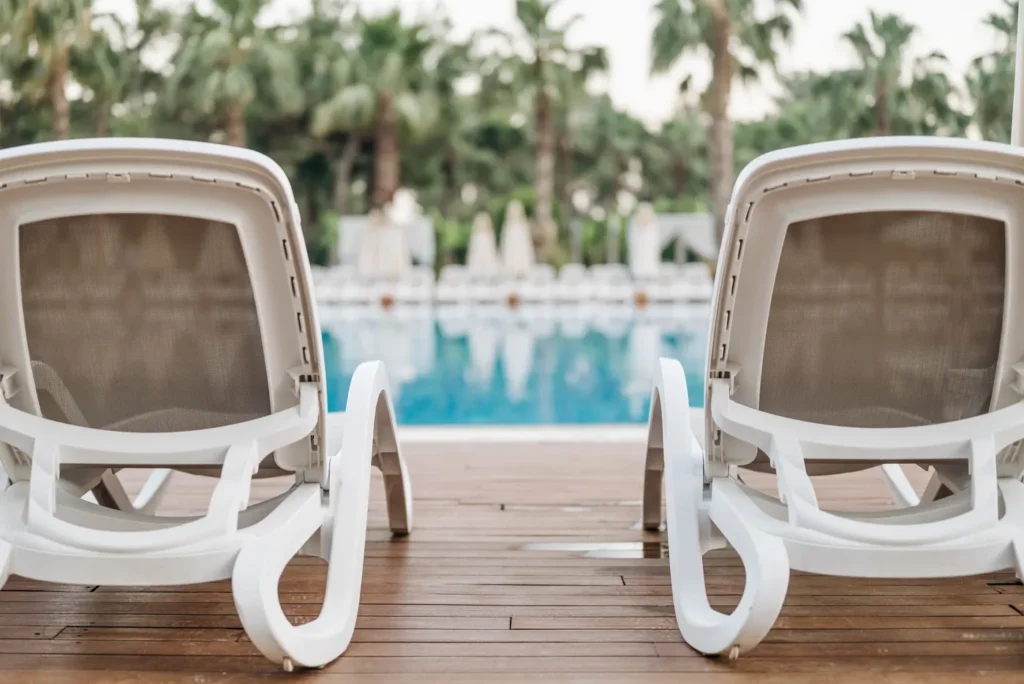 Two white loungers facing a pool