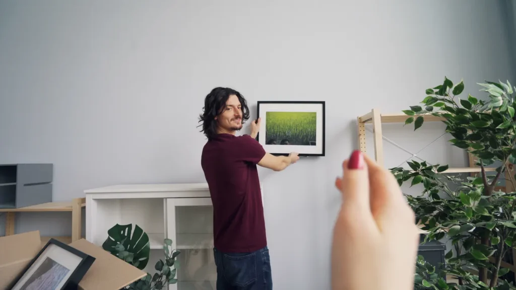 Woman fixing a frame to a wall above a cabinet