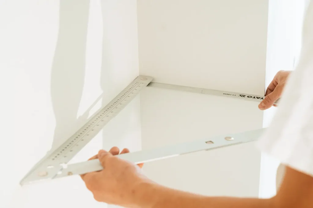 Hands fitting a white shelf to a wall