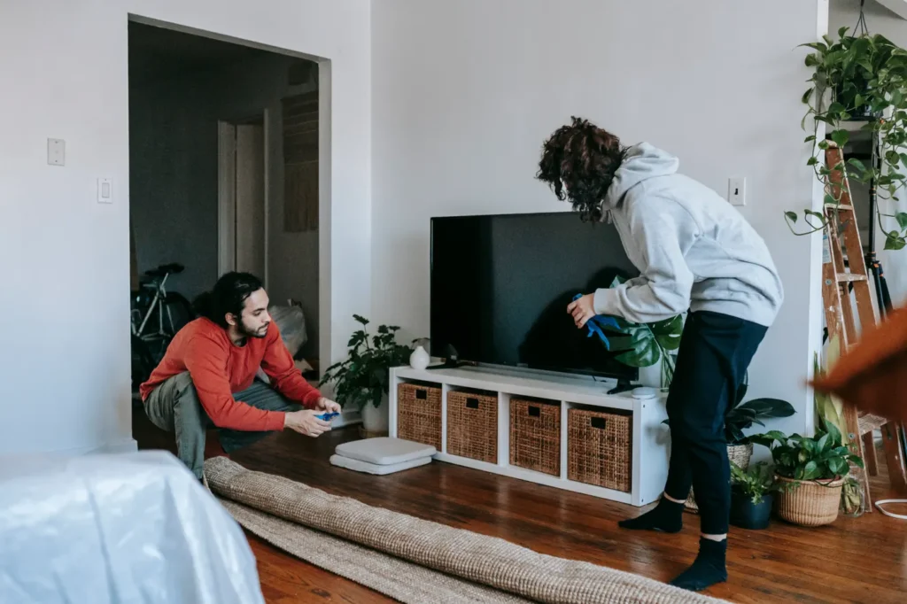 Man setting up a TV while a woman relaxes on the floor